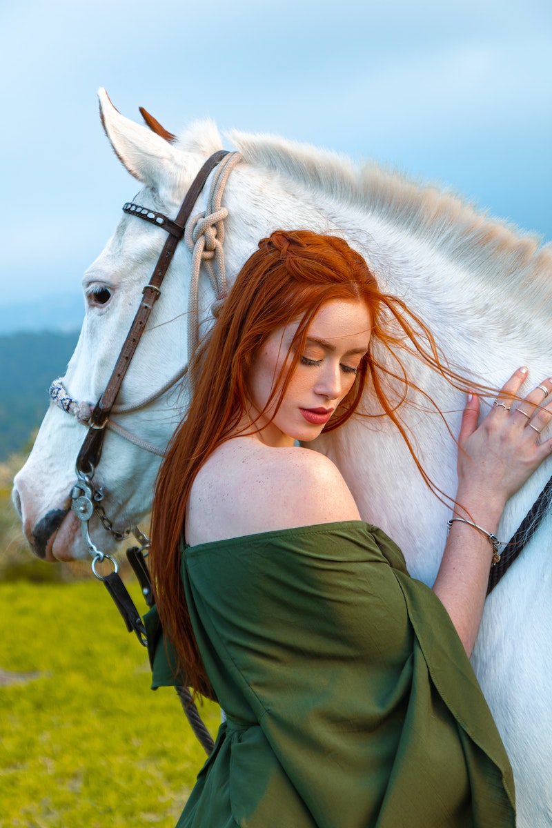 Redhead Woman Posing near White Horse. Stall drapes. Stall curtains.